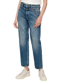 Jeans z wysokim stanem, prostą nogawką, w niebieskim denimu z wyblakłym wykończeniem i pięcioma kieszeniami, w połączeniu z jasnobeżowymi trampkami.