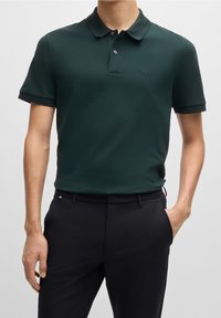 Mørkegrøn polo t-shirt med krave, korte ærmer og slim fit. Har et diskret brandlogo på brystet og kontrastfarvet ribbede ærmer.