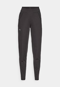 Leggings de sport noirs en tissu extensible, dotés d'une taille haute, de poches latérales et d'un petit logo réfléchissant sur la cuisse gauche.