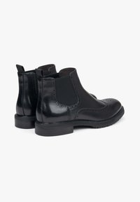 Czarne skórzane botki Chelsea z detalami w stylu brogue. Gładka faktura, elastyczne boczne panele, pętle do zakładania i trwała gumowa podeszwa.
