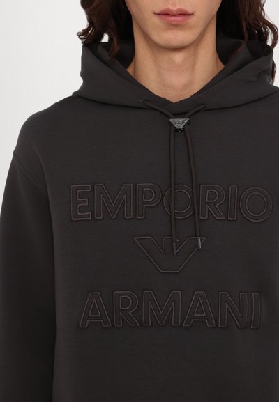 Hoodie cinza escuro com logo "Emporio Armani" em relevo. Cordão ajustável com acessórios em preto e um tecido suave e texturizado.