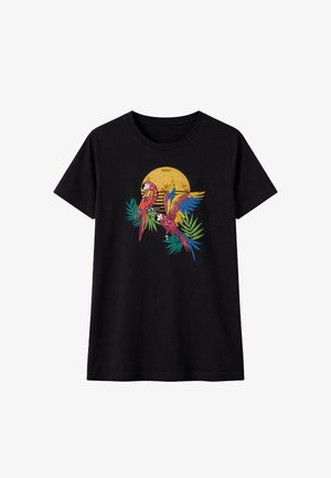 T-shirt nera con grafica colorata di due pappagalli, foglie tropicali verdi e uno sfondo giallo a raggi solari.