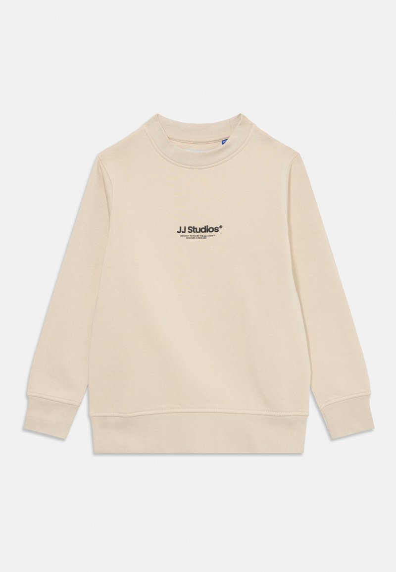 Bež dugih rukava pulover s crewneck izrezom s logotipom "JJ Studios" ispisanim crnom bojom u središtu prsnog dijela.