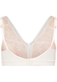 Trådlös bh i mjukt krämfärgat tyg med en spetsbak i ljus persika och nät detaljer. Har justerbara axelband och detaljer i guldfärg.