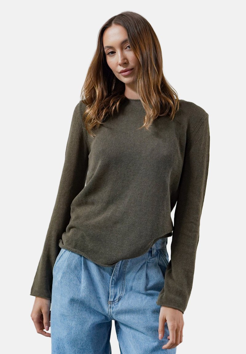 Olive green top z długim rękawem o prążkowanej fakturze z zaokrąglonym dołem. Stylizowany z jasnoniebieskimi dżinsami o wysokim stanie, charakteryzującymi się luźnym krojem.