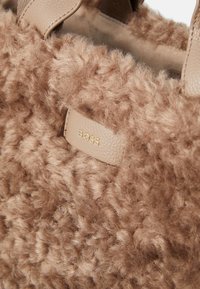 Faux fur draagtas in lichtbruin met een zachte, donzige textuur. Bevat een beige leren label met het goudkleurige reliëf "BOSS".