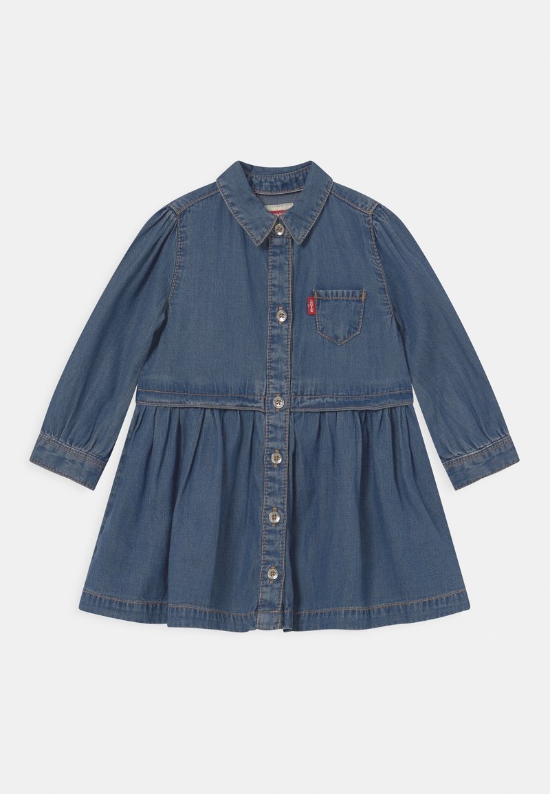 Robe en denim à manches longues boutonnée avec col, jupe froncée et poche poitrine avec étiquette rouge.