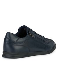 Zapatillas de cuero azul marino con un acabado suave, con cordones en la parte delantera, cremallera lateral para un acceso fácil y una suela de goma texturizada para mayor agarre.