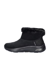 Zwarte enkellaars met een zachte nepbontkraag, suède bovenwerk en een flexibele rubberen zool met details voor arch support.