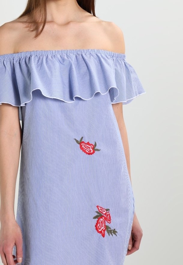 Pasiasta, niebieska sukienka z odkrytymi ramionami i falbaniastym dekoltem. Posiada czerwone hafty z kwiatami oraz luźny krój. Miękka faktura materiału.