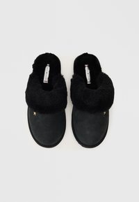 Μαύρα σουέτ παντόφλες με αφρώδη μαύρη επένδυση και μανσέτα. Διαθέτουν χρυσή λεπτομέρεια στο πλάι και ανθεκτική καουτσούκ σόλα.