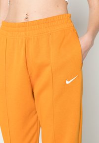 Nike Sportswear W NSW ESSNTL PANT FLC TREND - Calças de fato de treino - light curry/white