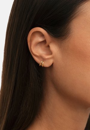 Pendientes de oro con un diseño liso y curvado, que presentan dos formas entrelazadas. Los pendientes tienen un acabado pulido y un brillo sutil.