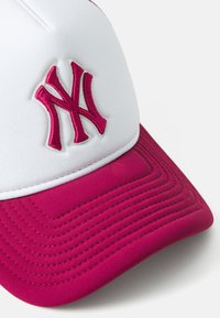 Cappello bianco con visiera rosa, caratterizzato da un logo 'NY' in grigio, ricamato in alta rilievo. La visiera presenta dettagli cuciti e testurizzati.