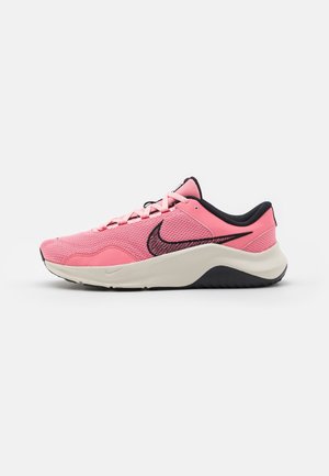 Baskets de sport pour homme roses avec logo swoosh noir, tige en mesh, semelle blanche amortissante et doublure de col noire, vue de côté sur fond blanc.