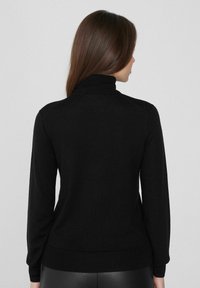 Suéter negro de cuello alto con mangas largas, cuello y dobladillo acanalados, textura lisa y forma ajustada. Diseño liso sin patrones.