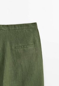 Pantalon en lin vert olive avec une ceinture cousue et une seule poche horizontale à l'arrière, sur fond blanc.