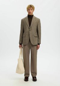 Brun hundetannsblazer over en mørk høyhalset genser, kombinert med beige bukser og en kremfarget totebag. Brukes med brune loafers.
