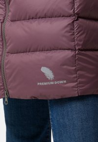 Puff-jakke i mauve med quiltet design, sølv lynlås og "Premium Down"-logo i hvidt på den nederste venstre panel.