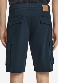 Mörkblå cargoshorts i tålig bomull, med stora sidofickor, en läderpatch bak och en rak ben-design.