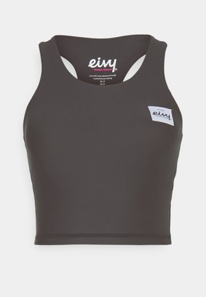 Schwarzes Sport-Crop-Top mit Rundhalsausschnitt und ausgeschnittenem Rücken. Verfügt über ein kleines weißes Stoff-Logolabel auf der Vorderseite. Glatte Textur.