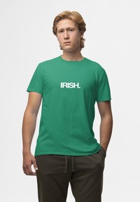 Zelené bavlněné tričko s nápisem "IRISH." tučným bílým písmem. Krátké rukávy, kulatý výstřih, hladká textura, volný střih.