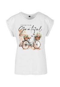 Bílý tričko s krátkým rukávem, který obsahuje akvarelovou ilustraci bicyklu s košíky květin a textem "Rozhodni se být vděčný."