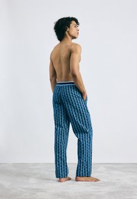 Blauwe broek met een geometrisch patroon, elastische tailleband met lichtblue accenten, gemaakt van een gladde, lichte stof.