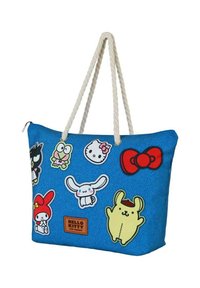 Bolsa de lona azul con asas de cuerda blanca, decorada con varios parches de personajes de dibujos animados coloridos y una etiqueta marrón de "Hello Kitty y Amigos".