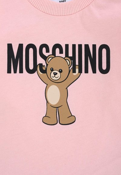 T-shirt en coton rose affichant un graphique d'ours en peluche brun avec les bras levés et le mot "MOSCHINO" en lettres noires gras au-dessus.