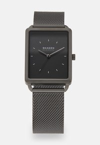 Montre carrée noire avec un cadran minimaliste, index des heures argentés, et un bracelet en métal maillé, offrant une finition mate et un design simple.