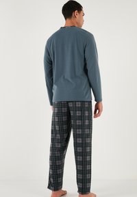 Sötét teal színű, hosszú ujjú felső, kerek nyakkivágással, és sötétzöld, szürke és fehér kockás mintájú pamut pizsama nadrág.