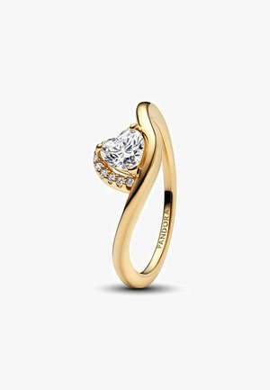 Anello dorato con un cristallo trasparente a forma di cuore sulla parte superiore, circondato da piccole pietre trasparenti lungo un lato, design della fascia liscia.