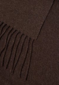 Puha barna gyapjú sál, rojtos végekkel, sík felületen elhelyezve.