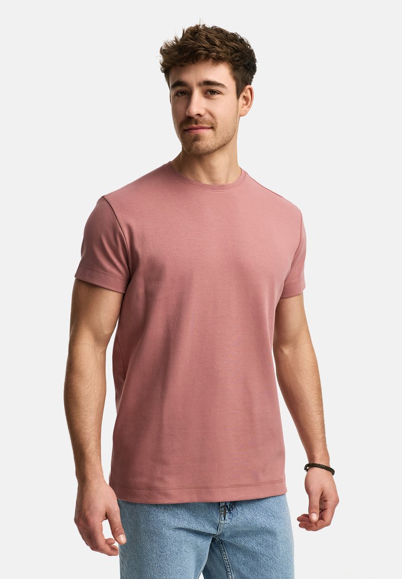 Camiseta de manga corta rosa con cuello redondo, hecha de un suave tejido de algodón. Presenta un corte relajado y detalles de costura sutiles.