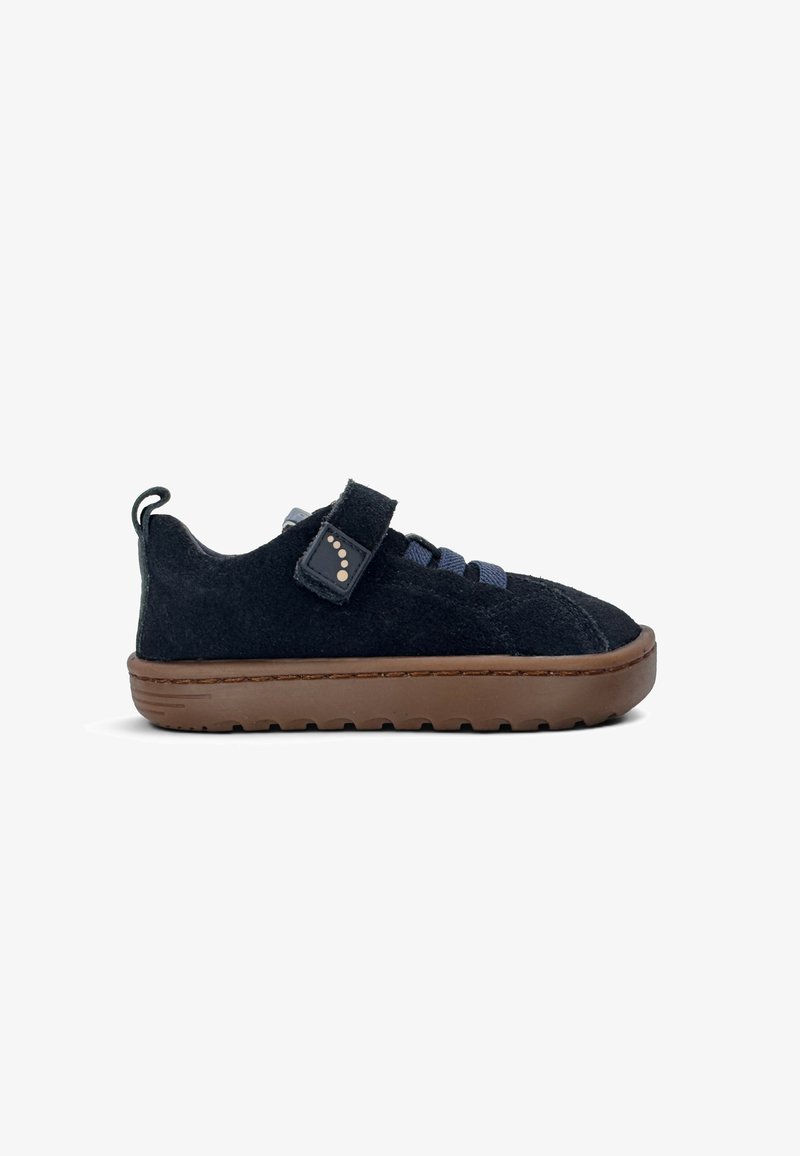 Chaussure basse en daim noir avec semelle en caoutchouc marron, lacets élastiques bleus et bride velcro noire avec un motif à pois sur le côté.