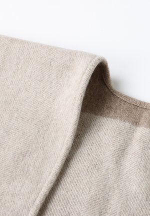 Beige wool blend fabric featuring a herringbone pattern, with a textured surface and a contrasting brown shade along the edge.