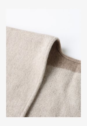 Beige wool blend fabric featuring a herringbone pattern, with a textured surface and a contrasting brown shade along the edge.