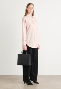 Light pink button-up shirt with long sleeves, paired with black wide-leg pants, black handbag, and pointed heels. Simple, clean design.