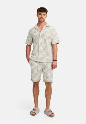 Lightweight, textured short-sleeve shirt and shorts set in a muted gray and white pattern. Paired with gray slide sandals.