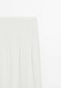 Lysegrå, plisseret stofnederdel med elastik i taljen. Glat tekstur, der falder under knæet. Simpelt design med minimal detaljering.