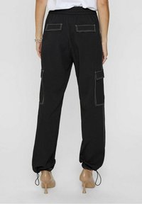 Pantalon cargo noir avec taille élastique, deux poches arrière et ourlets retroussés. Présente des coutures blanches contrastantes et des poches cargo latérales.