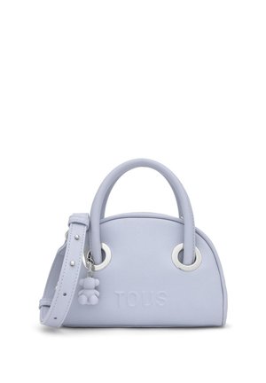 Jasnofioletowa skórzana torebka z zaokrąglonymi uchwytami, srebrnymi pierścieniami, regulowanym paskiem, tłoczonym logo "TOUS" oraz małą zawieszką w kształcie misia.