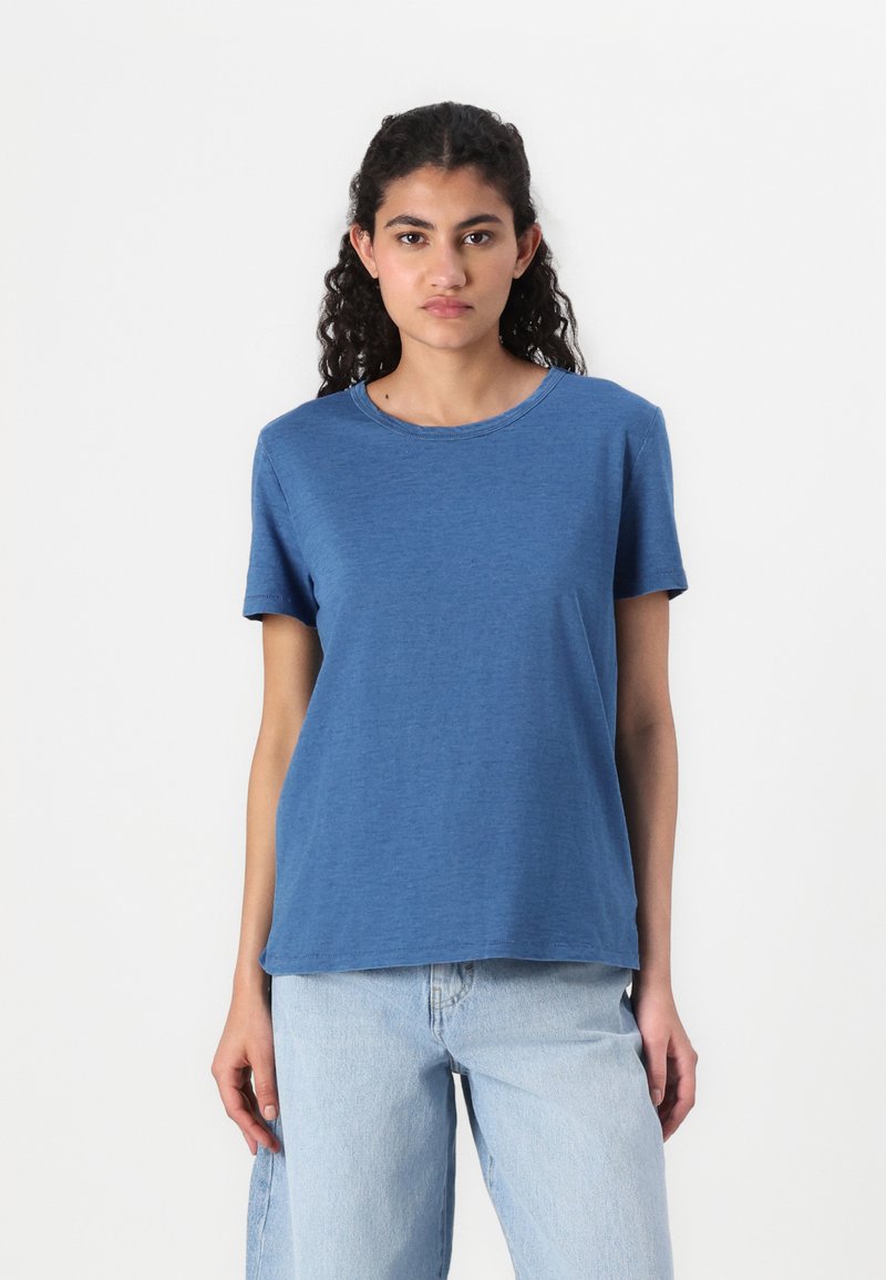 Blå kortermet t-skjorte laget av myk stoff, med rund hals og avslappet passform. Kombinert med lyseblå denimjeans.