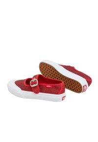 Zapatillas de lona rojas con purpurina, correa y hebilla a juego, suela de goma blanca y suela con patrón marrón. La marca está presente en el lateral.