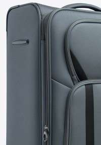 Grijze stoffen koffer met een gestructureerd oppervlak, voorzien van een rits, zwarte accentstreep en een zijhandvat. Schoon en modern design.