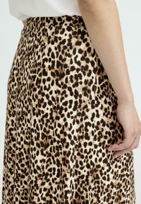 Leopardskirt i leopardmönster med en slät yta, brun och krämfärgad färgkombination, hög midja och detalj med sidoficka.