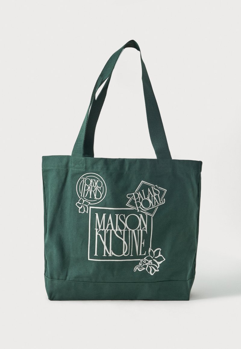 Mørkegrønn handlenett med brede håndtak med hvit grafisk tekst: "Maison Kitsuné," "Tokyo Paris" og "Palais Royal" med blomsterdetaljer.