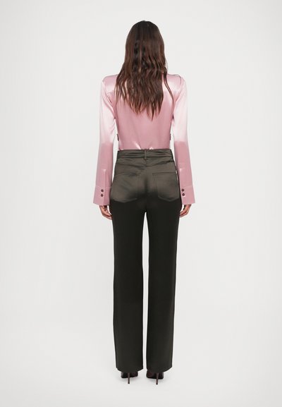 Top in satin rosa con maniche lunghe e gradiente, con polsini allungati; pantaloni a vita alta, verdi oliva, a gamba ampia, con tasche posteriori e dettagli con bottoni.