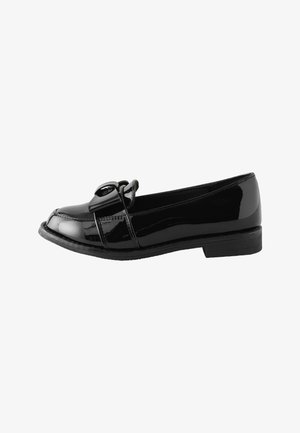 Mocassin en cuir verni noir avec un petit talon et une boucle décorative sur le dessus, présenté de profil sur fond blanc.